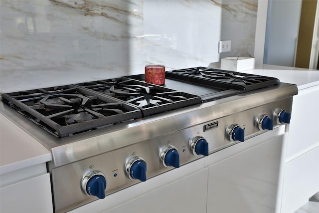 details with white cabinets, stainless steel range oven, and backsplash