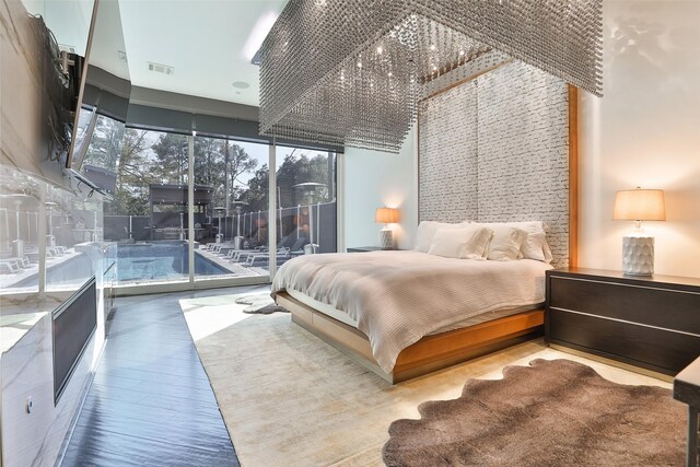 bedroom with access to outside, multiple windows, a towering ceiling, and wood-type flooring