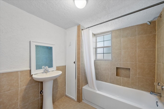 bathroom with a textured ceiling, shower / bath combo, tile walls, and tile patterned flooring