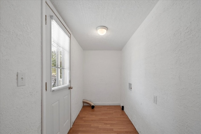 laundry area with hookup for a washing machine, a textured ceiling, and light hardwood / wood-style flooring