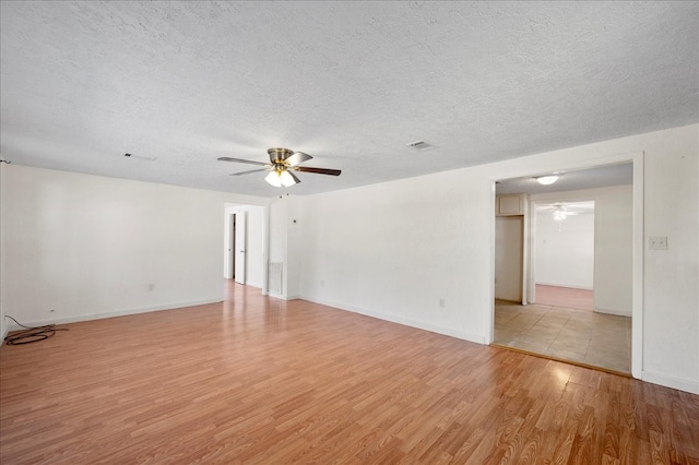 empty room featuring a textured ceiling, light wood-type flooring, and ceiling fan