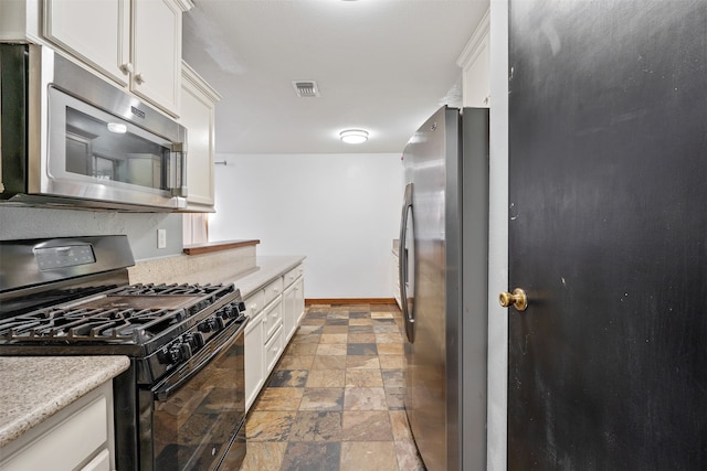 kitchen with light stone counters, stainless steel appliances, and white cabinets