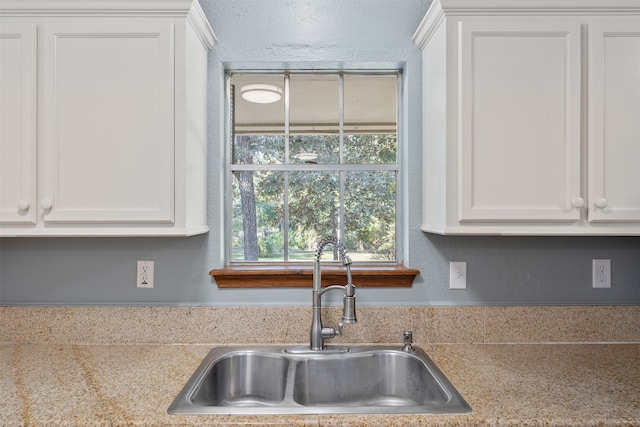 kitchen with white cabinets, light stone countertops, and sink