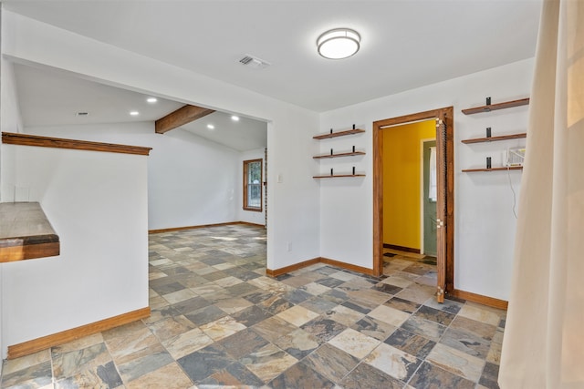 empty room featuring lofted ceiling with beams