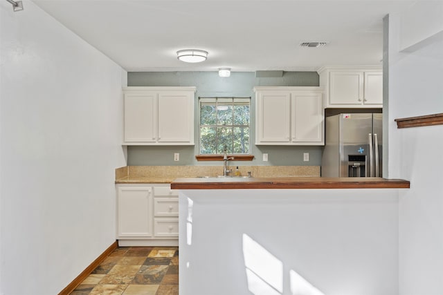 kitchen with white cabinetry, stainless steel fridge with ice dispenser, and sink