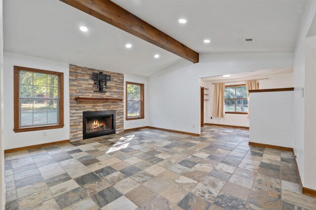 unfurnished living room featuring vaulted ceiling with beams, a stone fireplace, and a wealth of natural light