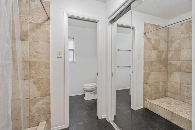 bathroom with concrete floors, toilet, and walk in shower