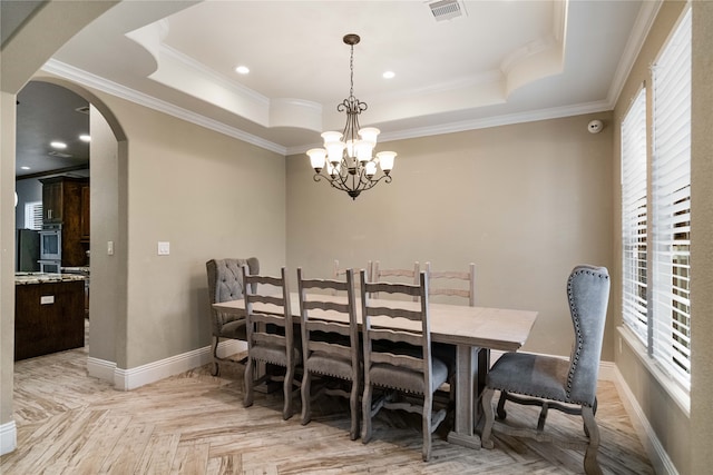 dining space featuring light parquet flooring, crown molding, an inviting chandelier, and a raised ceiling