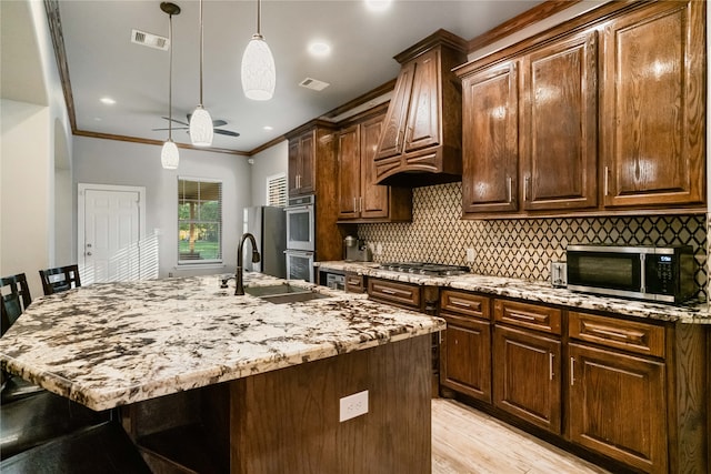 kitchen with sink, stainless steel appliances, ornamental molding, a breakfast bar, and a center island with sink