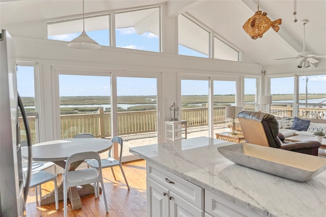 sunroom / solarium featuring lofted ceiling with beams, ceiling fan, a water view, and a wealth of natural light