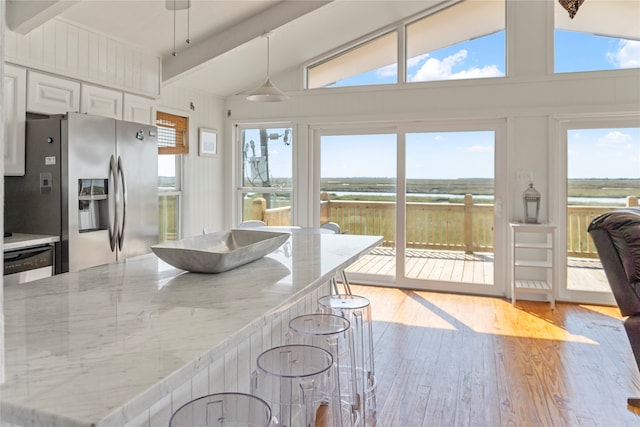 interior space with beam ceiling, stainless steel appliances, a wealth of natural light, and pendant lighting