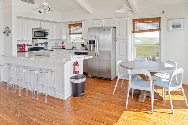 kitchen featuring beam ceiling, sink, white cabinetry, appliances with stainless steel finishes, and light hardwood / wood-style floors