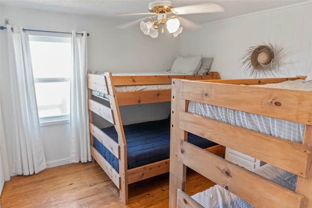 bedroom featuring light hardwood / wood-style flooring, a textured ceiling, and ceiling fan