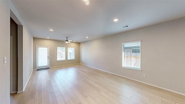 spare room featuring ceiling fan, light wood-type flooring, and plenty of natural light