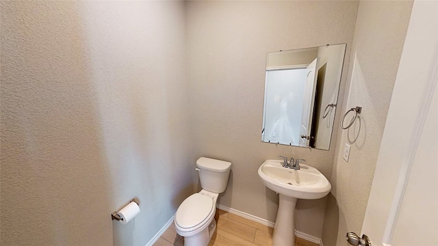 bathroom with toilet, sink, and wood-type flooring