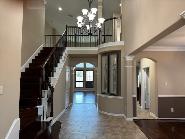 foyer entrance with hardwood / wood-style floors, crown molding, a towering ceiling, and decorative columns