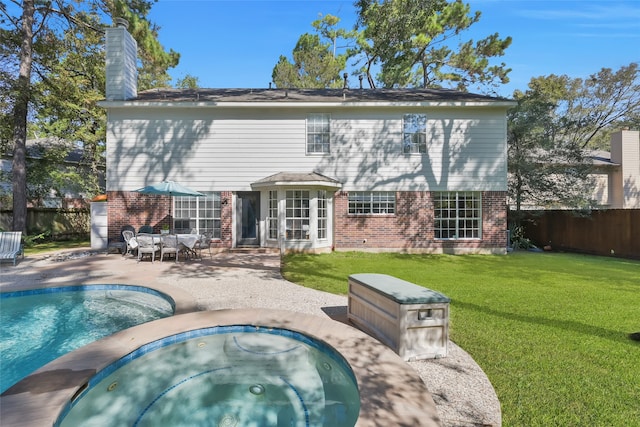 rear view of property featuring a yard, a patio area, and a pool with hot tub