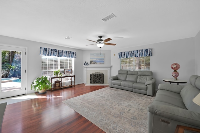 living room featuring ceiling fan, wood-type flooring, and a wealth of natural light