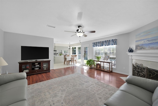 living room with ceiling fan, a textured ceiling, a fireplace, and hardwood / wood-style floors