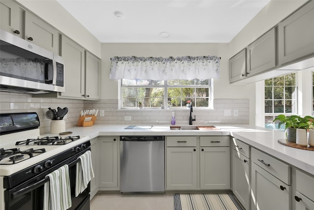 kitchen with tasteful backsplash, light tile patterned floors, sink, gray cabinets, and stainless steel appliances