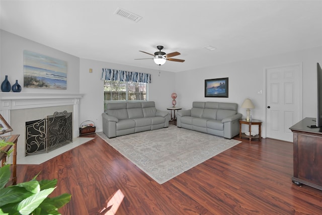 living room featuring dark wood-type flooring, ceiling fan, and a fireplace