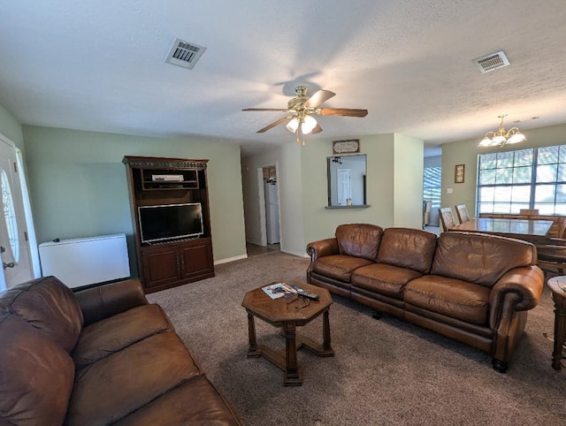 carpeted living room with a textured ceiling and ceiling fan with notable chandelier