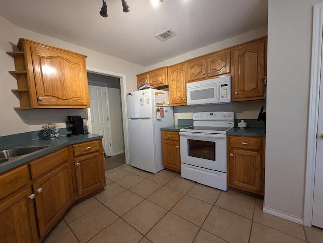 kitchen featuring white appliances, light tile patterned flooring, and sink