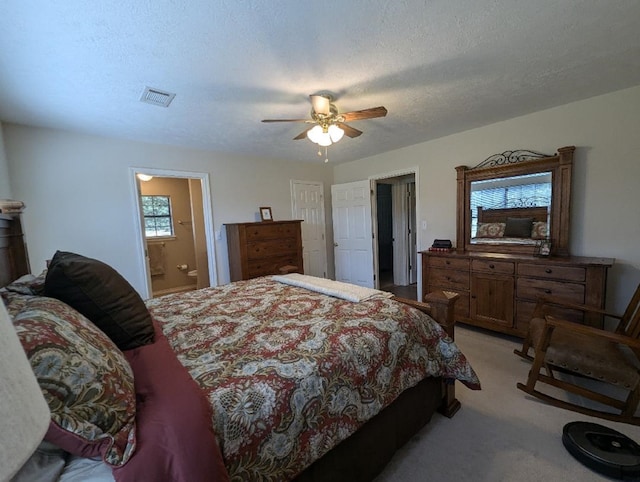 bedroom featuring multiple windows, a textured ceiling, ensuite bathroom, and ceiling fan