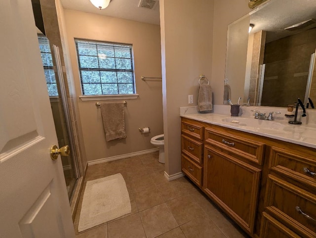 bathroom with toilet, tile patterned flooring, vanity, and a shower with door