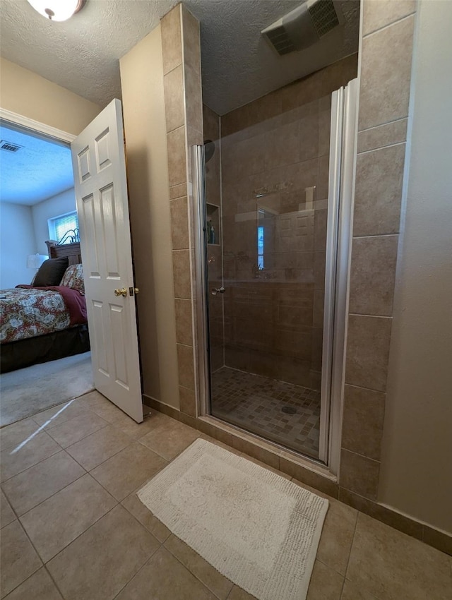 bathroom featuring a shower with shower door, a textured ceiling, and tile patterned flooring