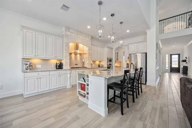 kitchen with visible vents, an island with sink, stainless steel appliances, white cabinetry, and pendant lighting