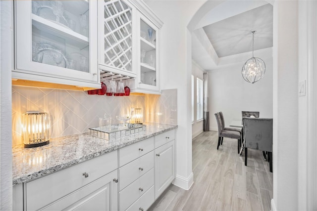 kitchen featuring glass insert cabinets, white cabinets, decorative backsplash, and decorative light fixtures