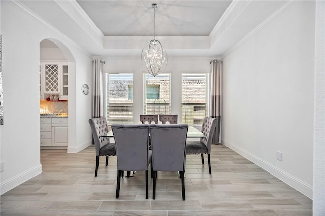 dining area with a tray ceiling, light wood-type flooring, and an inviting chandelier