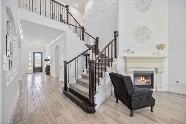 entrance foyer featuring wood tiled floor, a high ceiling, stairway, and a glass covered fireplace