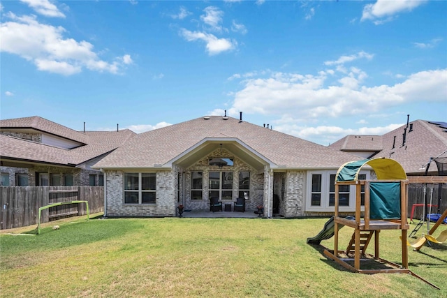 back of property featuring a shingled roof, a lawn, a playground, and fence private yard