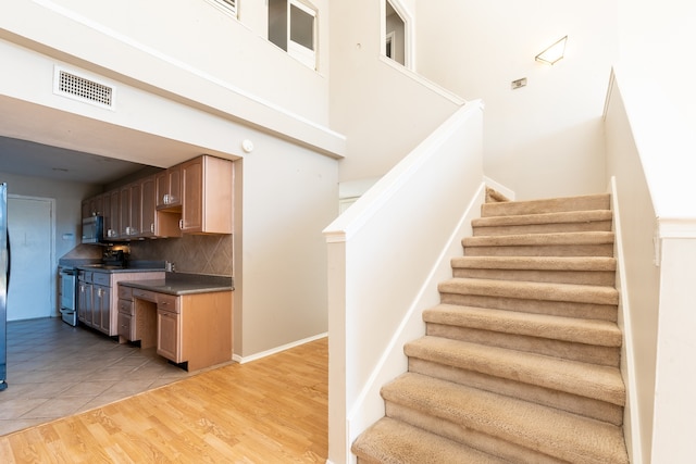 stairs featuring a high ceiling and wood-type flooring