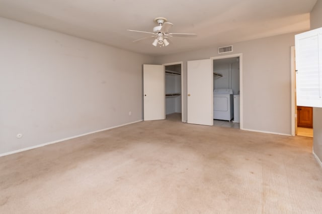 unfurnished bedroom featuring connected bathroom, ceiling fan, separate washer and dryer, and light colored carpet