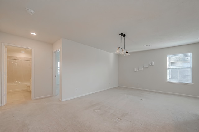 empty room with light carpet and an inviting chandelier