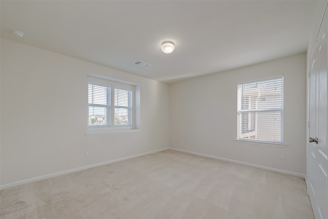 spare room with a wealth of natural light and light colored carpet