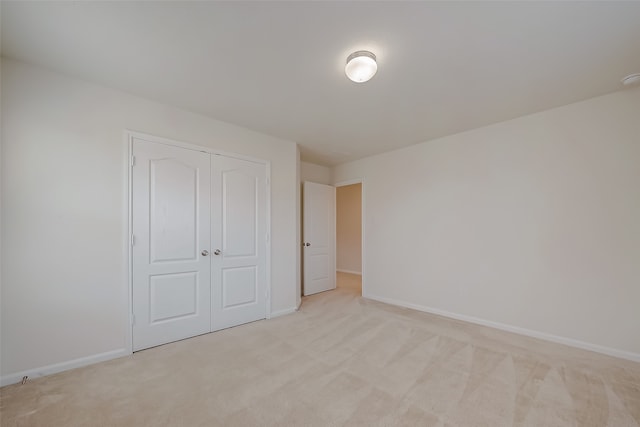 unfurnished bedroom with light carpet and a closet