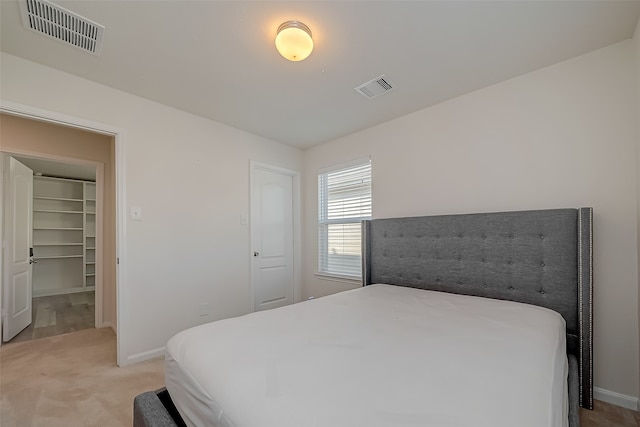 bedroom featuring light carpet, a walk in closet, and a closet