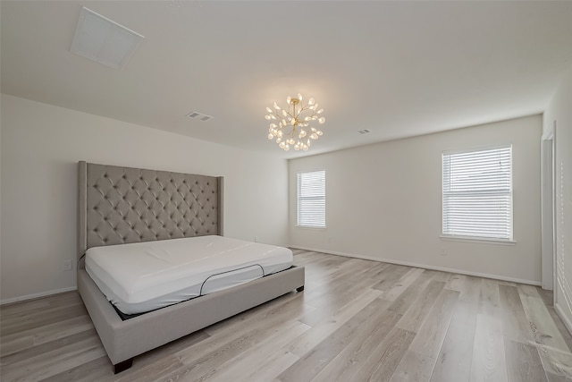 bedroom featuring light hardwood / wood-style floors, multiple windows, and an inviting chandelier