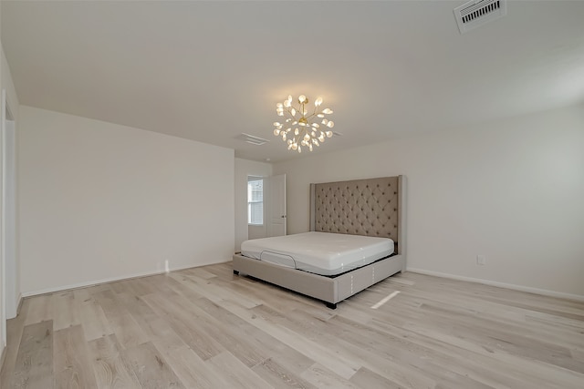 unfurnished bedroom featuring light hardwood / wood-style flooring and a notable chandelier