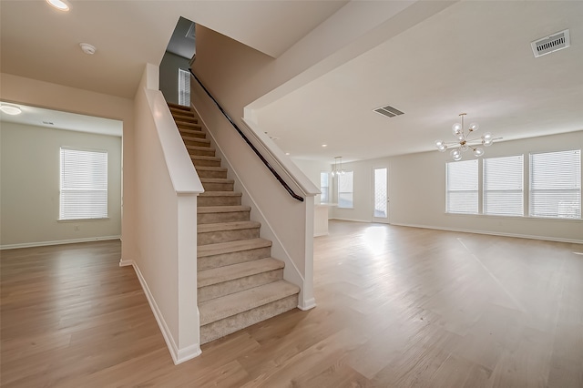 stairs featuring a notable chandelier and hardwood / wood-style floors