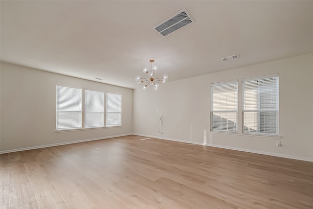 spare room featuring light hardwood / wood-style flooring and a chandelier