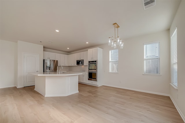 kitchen with sink, pendant lighting, white cabinetry, appliances with stainless steel finishes, and light hardwood / wood-style floors