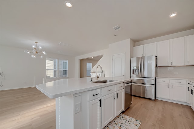 kitchen featuring appliances with stainless steel finishes, sink, white cabinets, light hardwood / wood-style flooring, and a kitchen island with sink