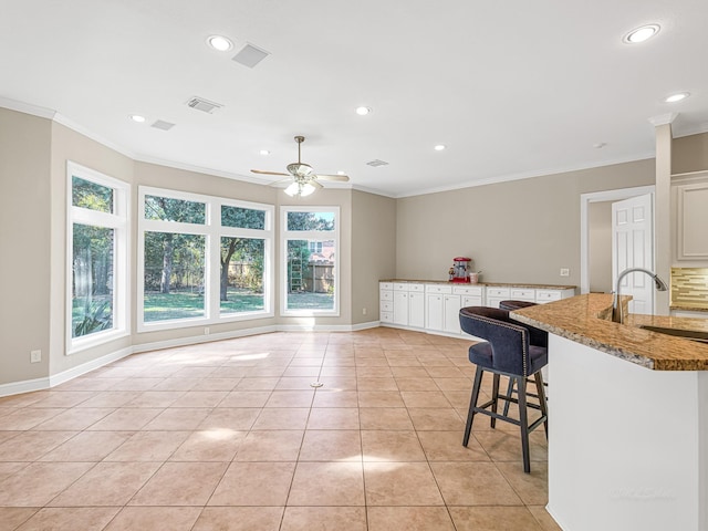 kitchen with dark stone countertops, a kitchen breakfast bar, white cabinets, and light tile patterned flooring