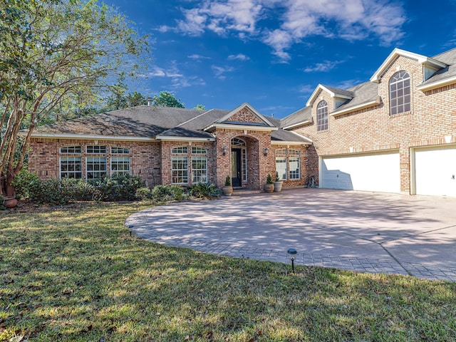 view of front facade with brick siding, decorative driveway, and a front lawn