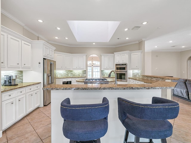 kitchen featuring appliances with stainless steel finishes, arched walkways, and ornamental molding